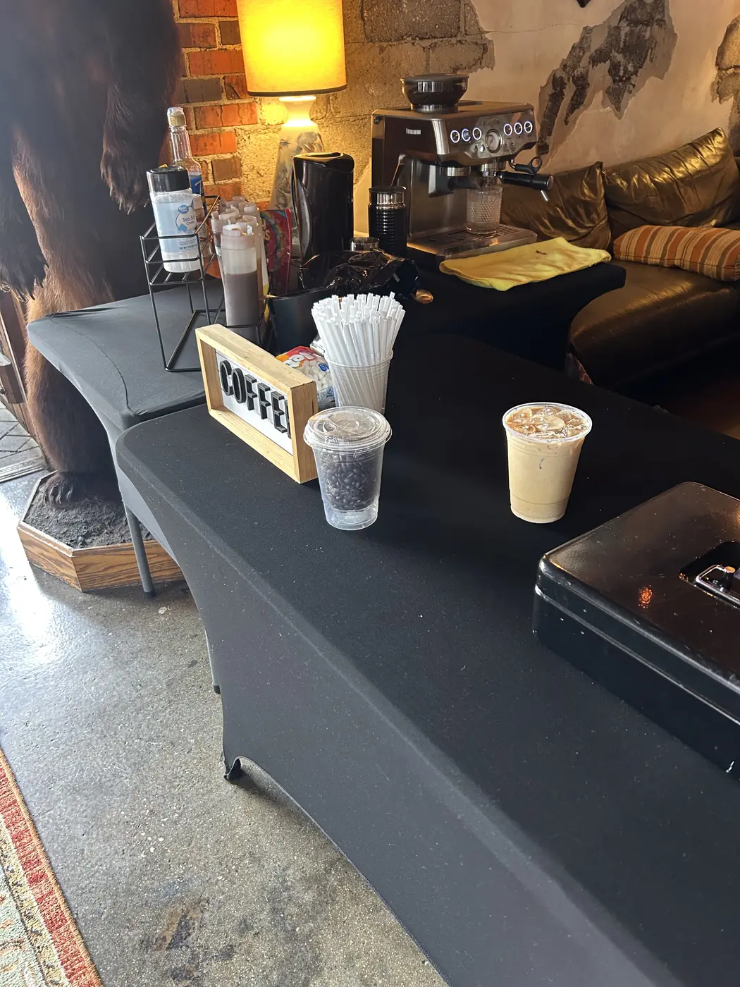 The table setup indoors, espresso machine and two finished drinks under a warm lamp.